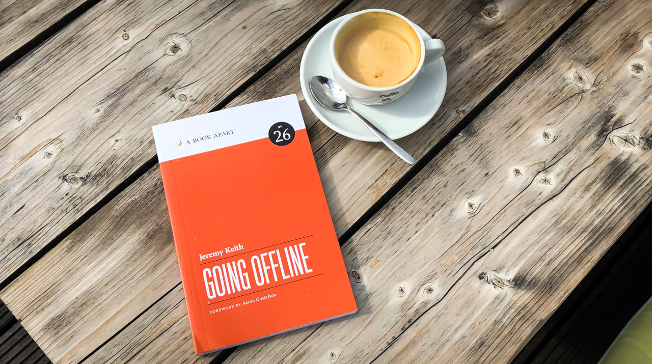Photo showing the book “Going Offline” and a cup of coffee on a wooden table