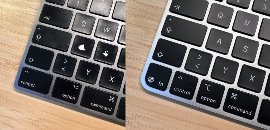 Side-by-side close-up comparison of two black Apple Magic Keyboards. The left keyboard is visibly worn, with a chipped and faded 'S' key and scuffs on surrounding keys. The right keyboard appears brand new, with crisp lettering and a clean finish. The new version also includes an additional 'fn' / globe key in the bottom-left corner.
