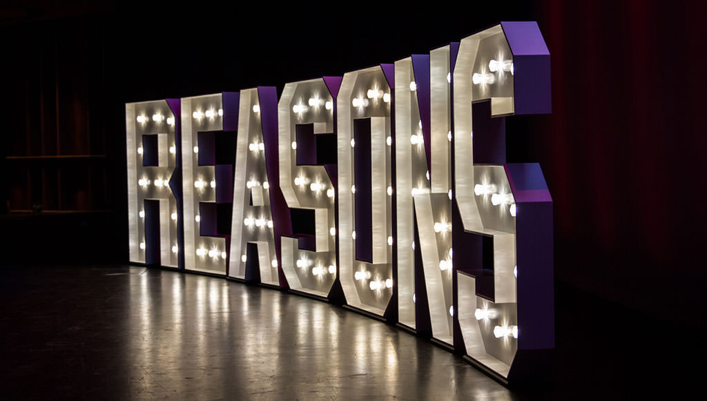 Light sign on stage of Reasons To