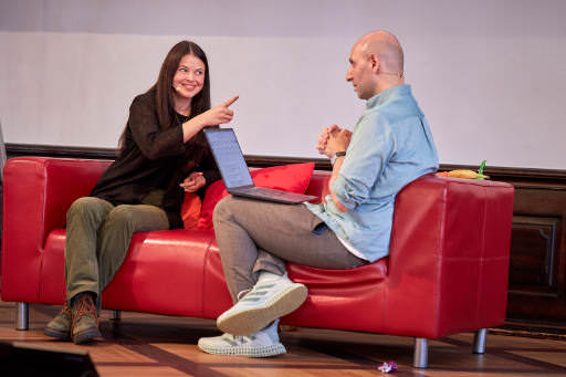 Ana Rodgriues on stage with Vitaly Friendman. They sit on a couch and Anna is pointing at Vitaly.