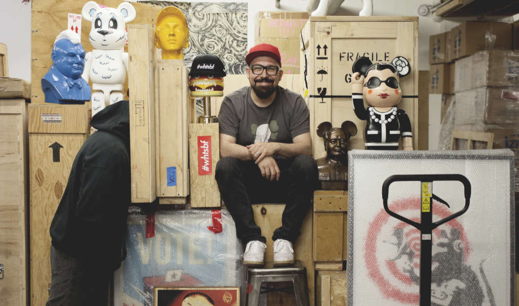 The photo is showing Selim Varol in his storage space, sitting on his packed, collected art.